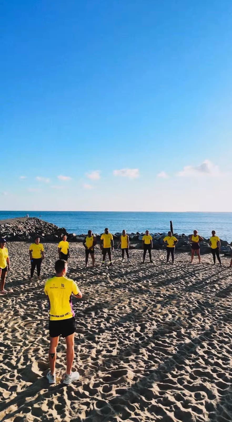 Roda de aquecimento na praia com o mar ao fundo
