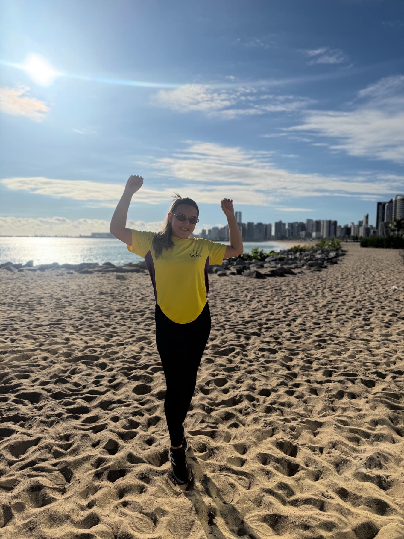 Participante comemorando de braços pra cima na praia