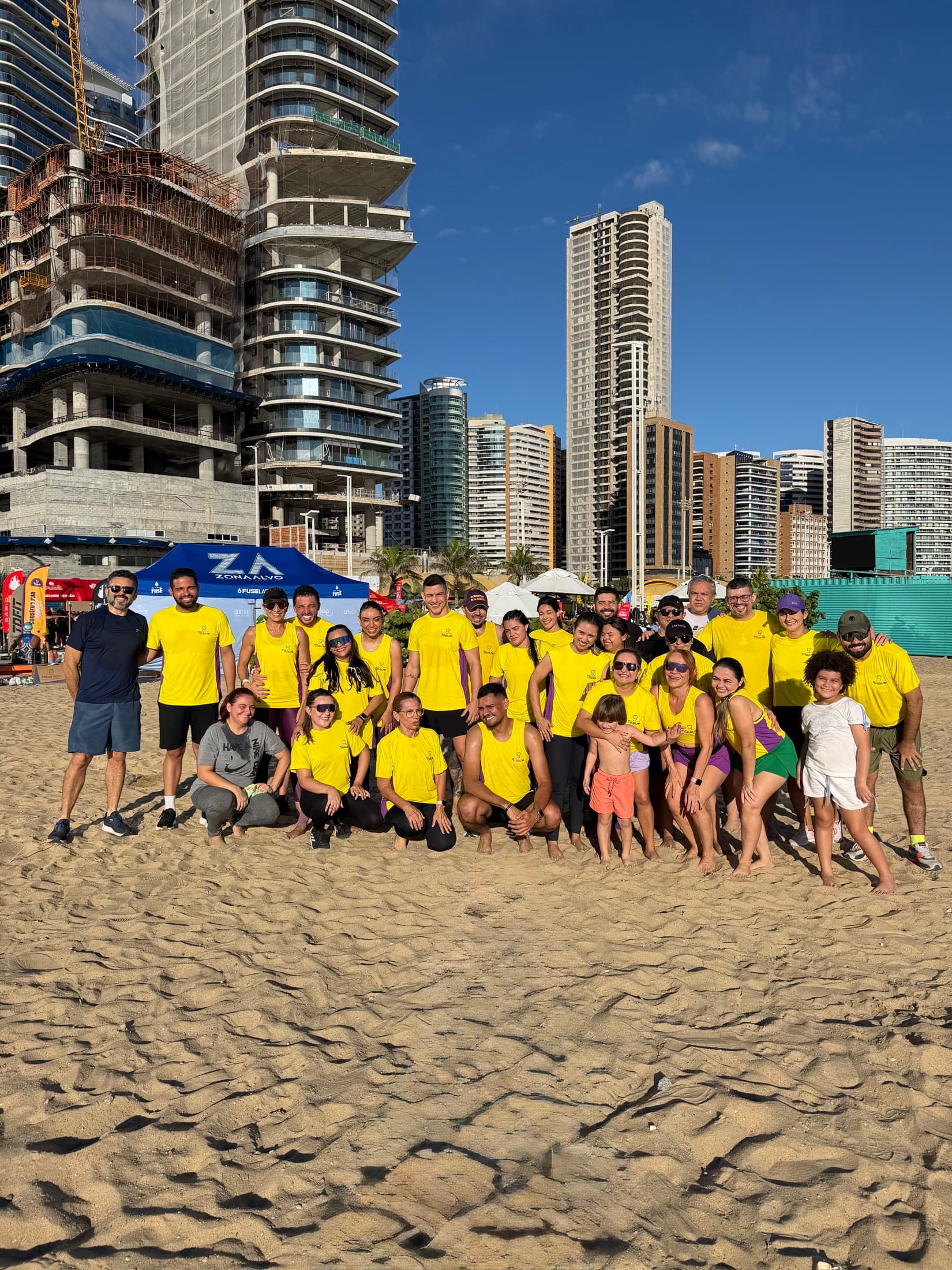 Colaboradores Trevo de camisa amarela reunidos na areia da praia depois do treino